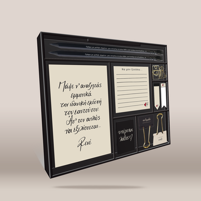 A framed blackboard-style wall art piece with cream writing panels, decorative labels, ribbon bookmarks, paperclips, and small printed inserts, shown at an angle on a plain beige background.