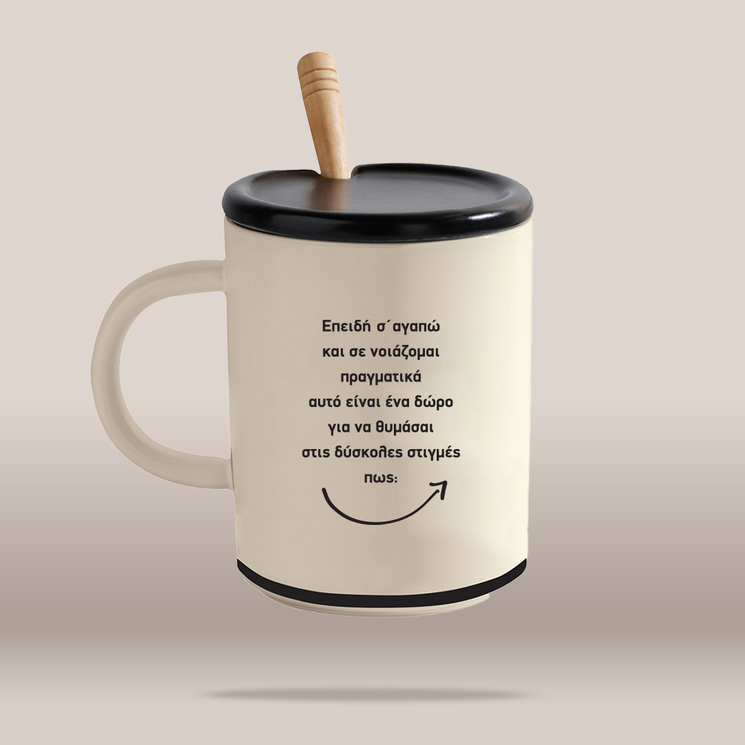 An off-white ceramic mug with a black lid and handle, featuring a light wood spoon handle and black Greek text printed on the front, set against a solid beige background.