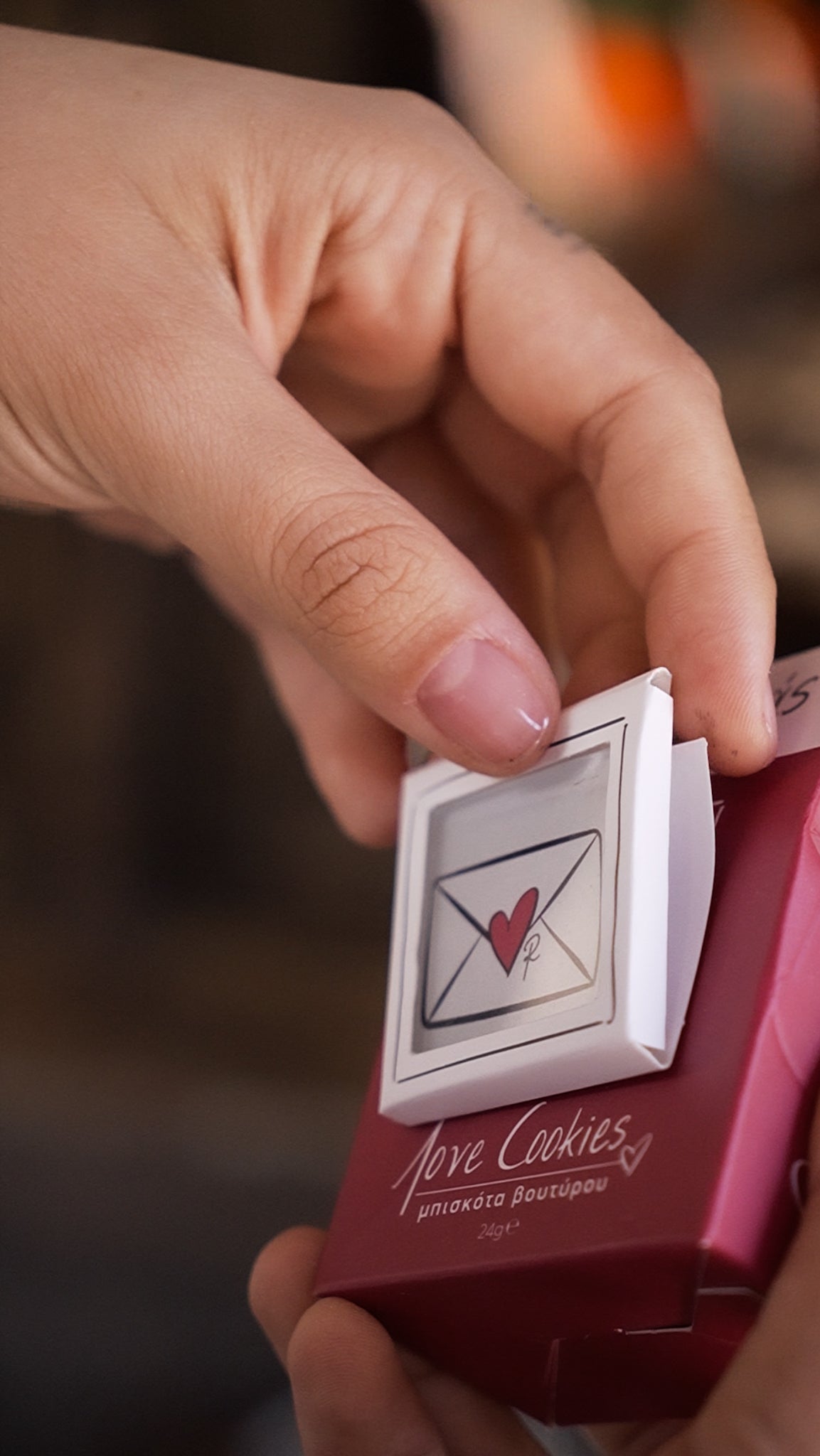 Hand holding a small box with a heart design and 'Fever Cookies' branding.