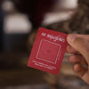 Hand holding a red card with text against a blurred background
