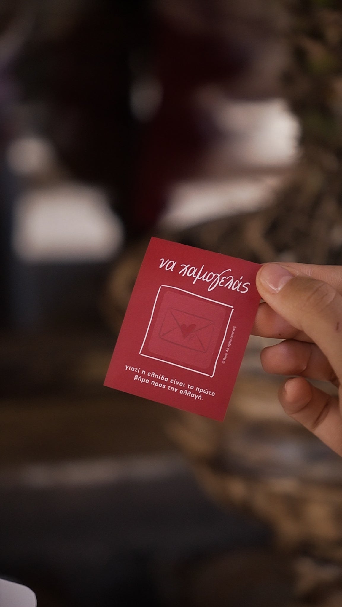 Hand holding a red card with text against a blurred background