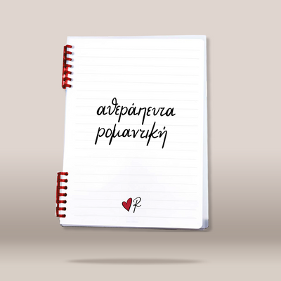 A white lined spiral notebook with red spiral binding, featuring the Greek text  in black script and a small red heart with a black 'R' at the bottom, shown on a neutral beige background.