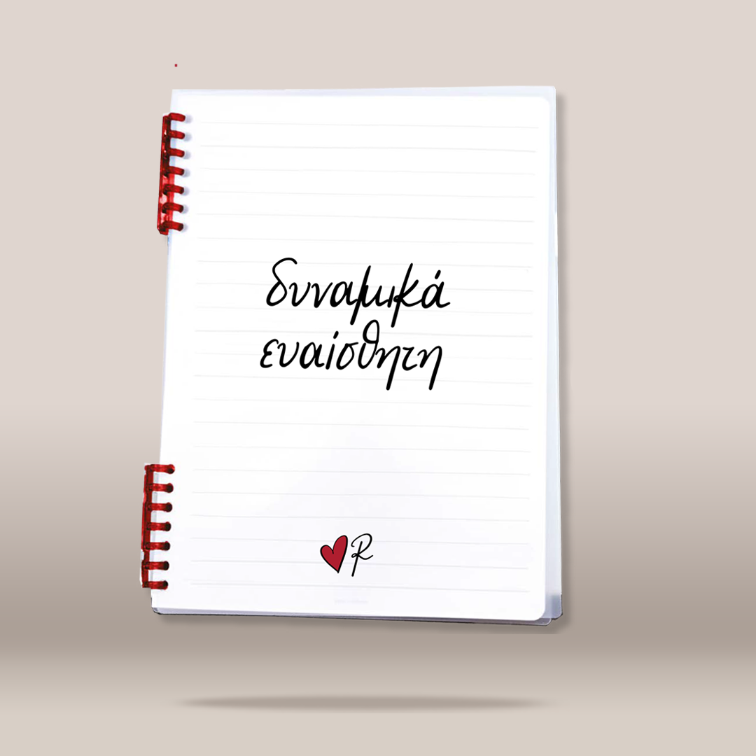 A white lined spiral notebook with red spiral binding, featuring the Greek text  written in black script on the cover, with a small red heart and black 'R' logo at the bottom, shown floating against a neutral beige background.