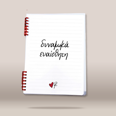 A white lined spiral notebook with red spiral binding, featuring the Greek text  written in black script on the cover, with a small red heart and black 'R' logo at the bottom, shown floating against a neutral beige background.