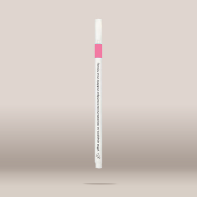 A single white cosmetic pen-style applicator with a pink band near the top and black printed text, shown centered against a soft beige gradient background.