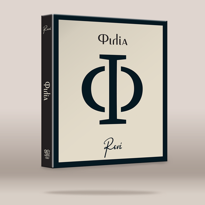 A boxed product package shown at a slight angle on a plain beige studio background. The front is cream with a large dark navy monogram and the words “ΦΙΛΙΑ” in dark navy, and the spine is dark navy with white text.