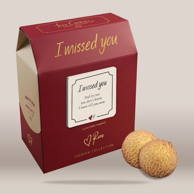 A red gift box with gold lettering reading 'best wishes' and 'Pene Premium Collection' on a light beige background, with two round butter cookies placed in front of the box.