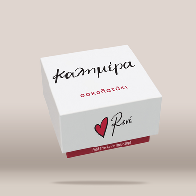 A white rectangular gift box with black and red printed text and logo, shown floating at an angle against a warm beige gradient background. The box features the Greek word 'ΚΑΛΗΜΕΡΑ' below it, a red heart logo next to the script 'Revé' on the front, and the phrase 'find the love message' on a red band at the bottom.