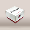 A white square gift box with red base and custom printed text and heart logo, shown floating on a light beige background.