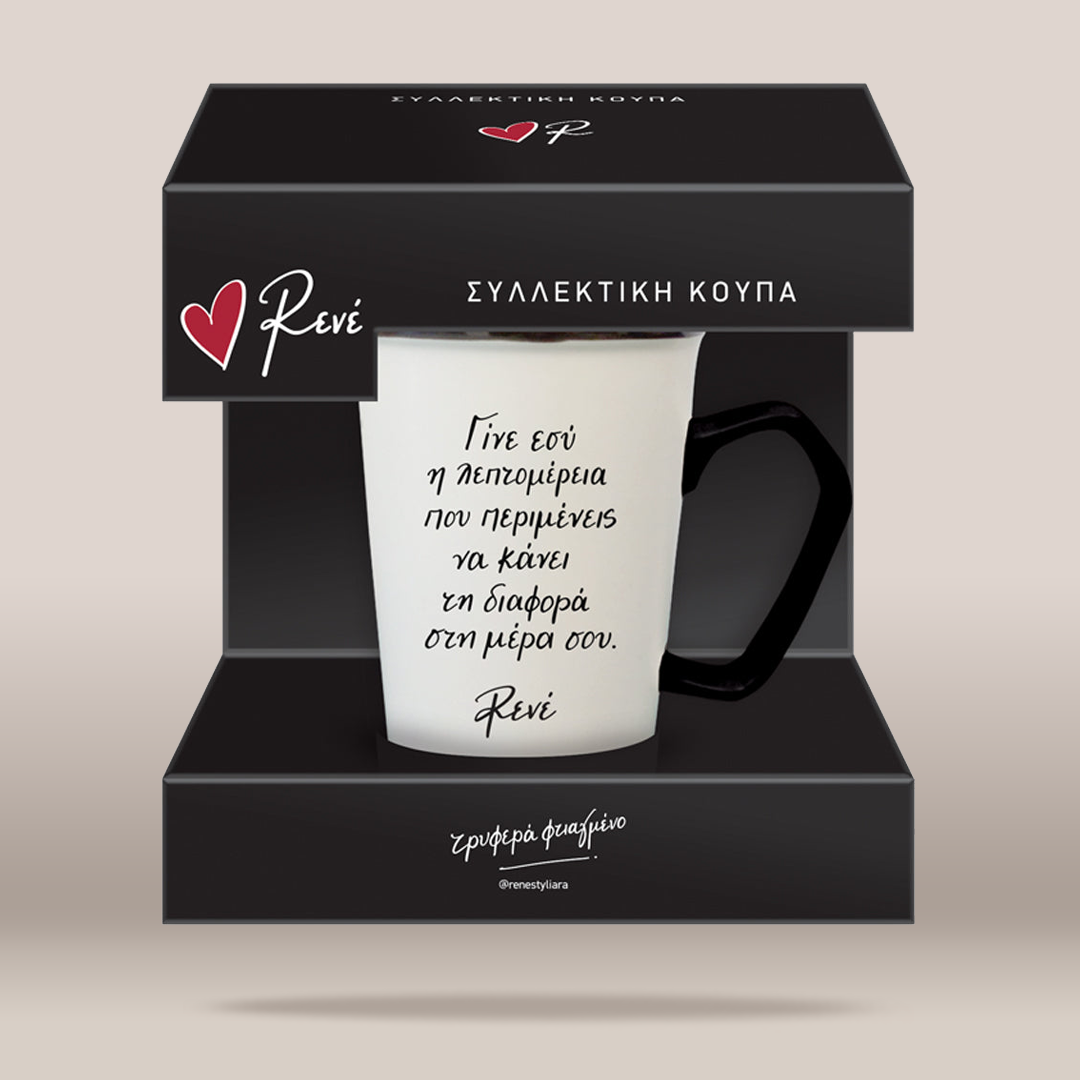 A white ceramic mug with a black handle and black Greek text, presented inside a black gift box with the brand name Reví visible on the packaging.