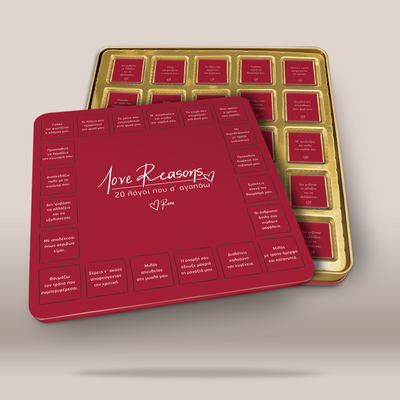 A red square gift box with a hinged lid, shown in front of an open gold-toned tray containing multiple small red cards or inserts. The lid has white script text reading 'Love Reasons' and Greek text arranged around the perimeter.