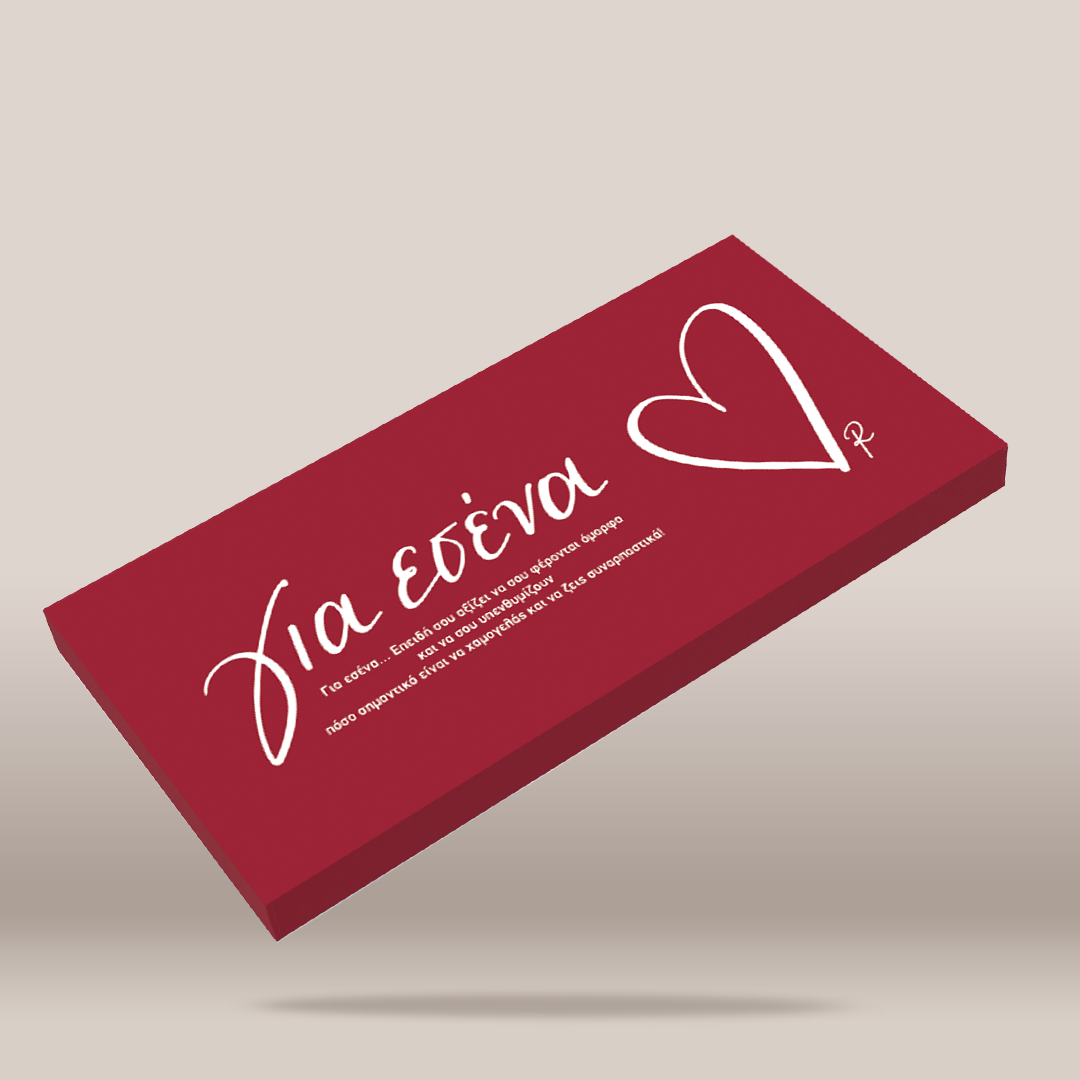 A rectangular red box with white cursive Greek text and a white outlined heart, shown floating at an angle on a light beige background.