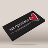 A black rectangular product box shown at an angle on a light beige background. The box has white Greek text and a red heart graphic on the top surface.