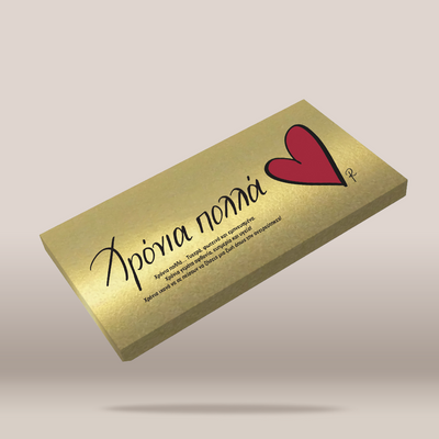 A rectangular gold box with a red heart and black script text, shown floating at an angle against a light beige background.