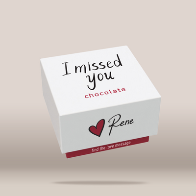 A white square chocolate box floating against a warm beige background, printed with the words 'I missed you' in black script, 'chocolate' in red lowercase text, the name 'Rene' with a red heart, and a red strip reading 'find the love message'.