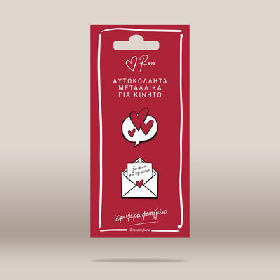 Two small heart-themed metal pins on a red hanging card, photographed against a light beige gradient background. The top pin shows overlapping red and white hearts, and the bottom pin shows an open white envelope with a red heart and Greek text.