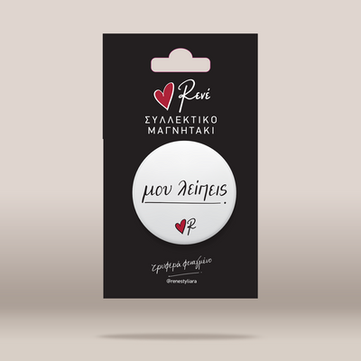 A white circular magnetic button with black cursive text and a small red heart logo, mounted on a black retail backing card with Greek text and the brand name Rene.