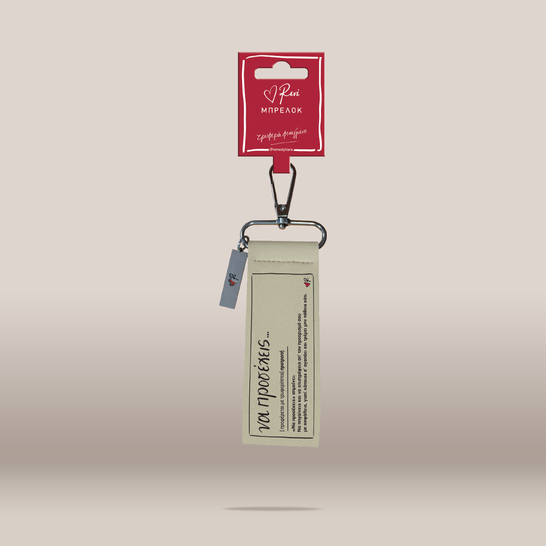 A cream-colored leather keychain with a black metal clasp and a small blue tag, attached to a red cardboard hanger card with white text, set against a solid beige background.