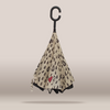 A reverse umbrella with a beige background and a black raindrop pattern, featuring a small red heart with a white key in the center. The handle is a black C-shaped hook, shown against a neutral beige background.