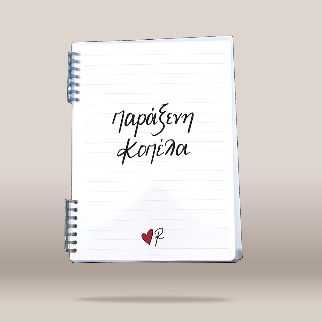 A white spiral-bound lined notebook floating against a warm beige gradient background. The notebook has black handwritten-style Greek text on the cover and a small red heart with a black script mark near the bottom.