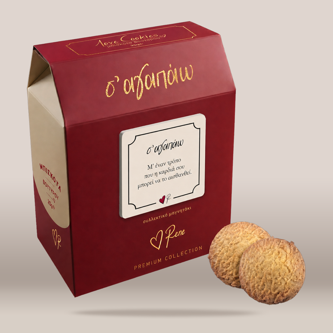 A red bakery box with gold lettering and a white label, shown on a light beige background with two round cookies placed in front. The box appears to be the product packaging for the cookies.