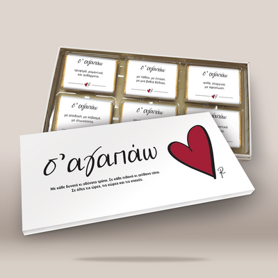A boxed set of six small white cards with Greek text, arranged in a clear tray behind a larger matching card in front. The front card has black script text and a large red heart on a white background.