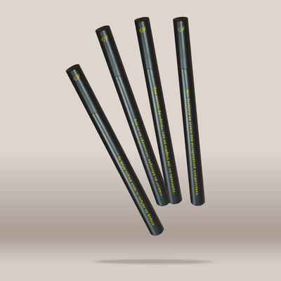 Four slim black cosmetic tubes arranged diagonally on a soft beige gradient background. Each tube has yellow text and a small yellow logo near the top.