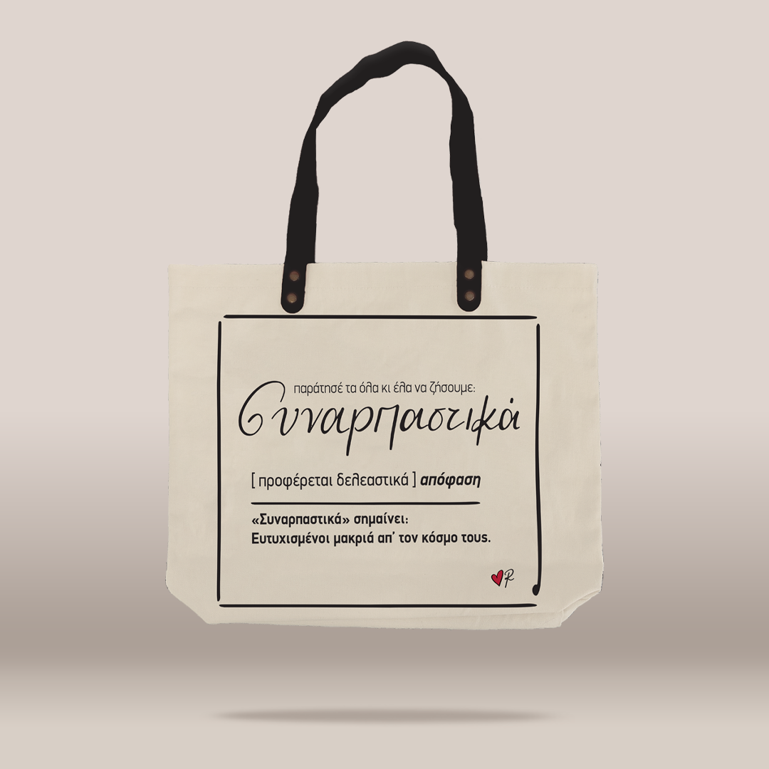 An off-white canvas tote bag with black handles and black printed Greek text on the front, shown against a solid light beige background.