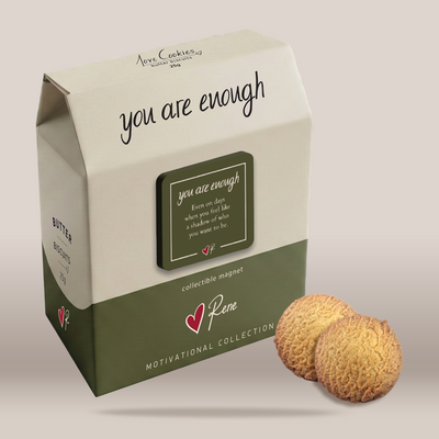 A milk carton-style product box with the words 'you are enough' and a collectible magnet label, shown on a plain light beige background with two round textured cookies placed in front.